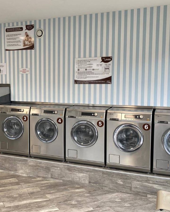 Rangée de lave-linges professionnels numérotés dans la laverie des Villages à Saint-Brieuc